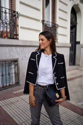 a lady weas a black tweed jacket with white T-shirt and jeans
